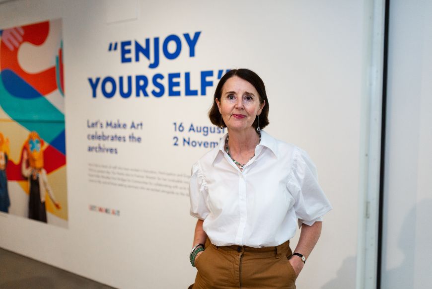 a woman stands outside a gallery smiling